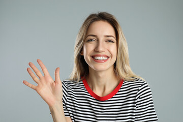 Woman showing number five with her hand on light grey background