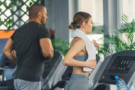view of a young man and woman on the treadmill at the gym, medium shot. High quality photo
