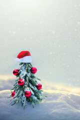 Christmas tree with red Santa hat on white snow.