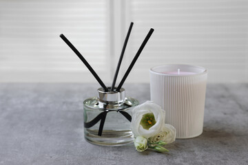 Reed diffuser, scented candle and eustoma flowers on gray marble table