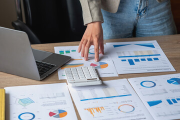 Marketing, Financial, Accounting, Planning, business women analyze company results and profits with graph statistics. Use a laptop computer and a calculator to calculate the company's balance.