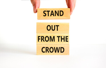 Stand out from the crowd symbol. Concept words Stand out from the crowd on wooden blocks on beautiful white table white background. Businessman hand. Business, stand out from the crowd concept