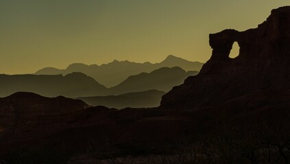 Scenic view of a yellow sky at sunset with silhouettes of hills in the distance in the countryside - Powered by Adobe