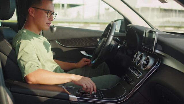 Young asian man driver in car, sharing concept, vehicle and premium transport. Korean happy guy driving, sitting in new luxury car and smiling. Traveling by automobile.