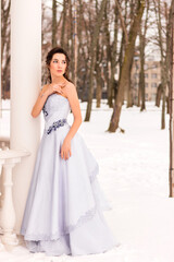 Fototapeta na wymiar Beautiful woman in a luxurious blue fairy-tale dress in a snowy forest