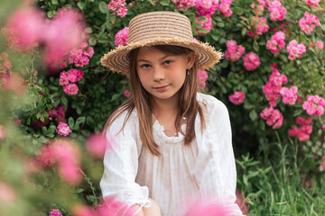 portrait of a beautiful girl among pink roses outside