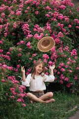 Summer stories of a little girl. White T-shirt. Straw hat. Pink roses.