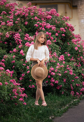 Summer stories of a little girl. White T-shirt. Straw hat. Pink roses.