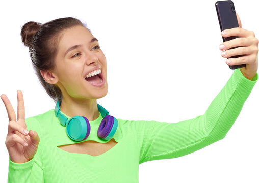 Pretty teenage girl with wireless headphones around neck, taking selfie for social networks
