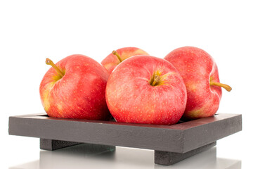 Several juicy red apples on a black wooden tray, macro, isolated on white background.