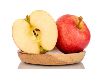 One whole and one half juicy red apples on a wooden plate, macro, isolated on white background.