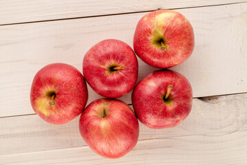 Several sweet red apples on a wooden table, macro, top view.