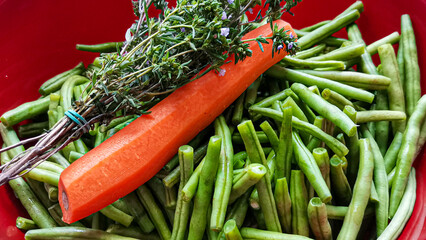 Frische grüne Bohnen in einer Schüssel mit Karotte und Bohnenkraut