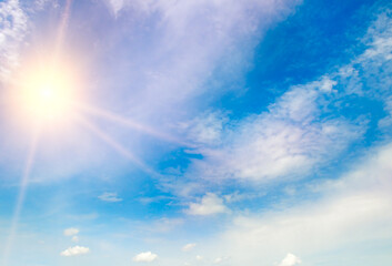 Naklejka na ściany i meble Blue sky with fluffy clouds and bright sun as a background