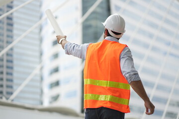 Architect or engineer with blueprints. Cauacsian Engineer checking plan on construction site. modern structure. helmet and blueprints paper.