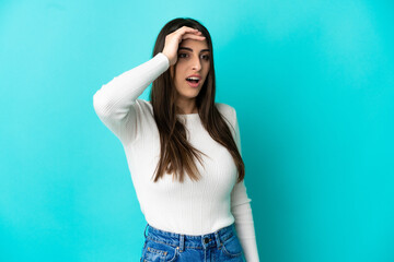 Young caucasian woman isolated on blue background with surprise expression while looking side