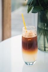 Espresso tonic in a glass with a yellow drinking straw.