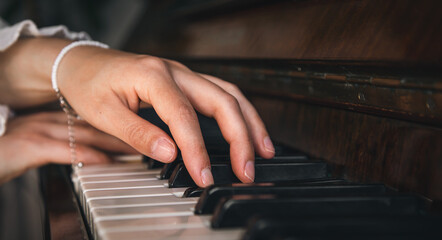 Fototapeta premium Female hands playing the old piano, close-up.