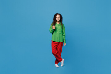 Full body young woman of African American ethnicity 20s wear green shirt hold takeaway delivery craft paper brown cup coffee to go isolated on plain blue background studio People lifestyle concept.