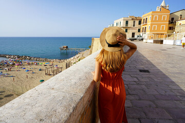 Back view of young woman walking in the historic town of Termoli, Molise, Italy - obrazy, fototapety, plakaty