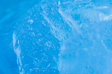 Global warming. Melting blue ice macro shot. Natural crystal clear flowing water. Creative background