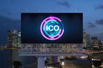 ICO hologram icon on billboard over panorama city view of Singapore at night time. The hub of blockchain projects in Southeast Asia. The concept of initial coin offering, decentralized finance