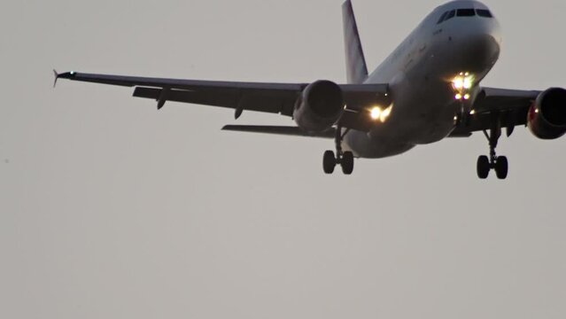The plane with the lights on is going to land. Slow motion video close-up of an airplane in flight. High quality 4k footage