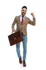 happy young businessman with suitcase holding fist in the air