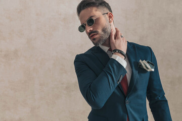 attractive businessman in suit with sunglasses holding hand behind neck
