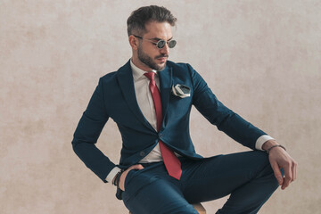 seated elegant businessman with hand in pocket looking to side