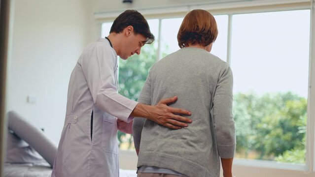 Young doctor helping senior elderly woman walk to patien bed in the room.