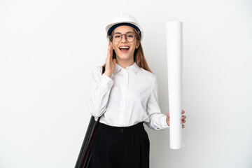 Young architect woman with helmet and holding blueprints isolated on white background shouting with...