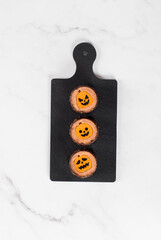 Halloween. Themed small round mousse chocolate cake with pumpkin jelly, on a serving board. Light background. Top view