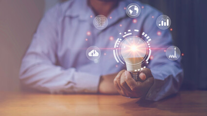 Businessman holding glowing lightbulb with learning icons for study knowledge to creative thinking idea and problem solving solution concept.