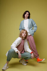 High fashion photo of a beautiful elegant young women in a pretty white, pink and green mint sports suit oversize, jacket, walking style, posing over yellow background. Studio Shot. Portrait.