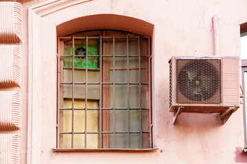 Fototapeta na wymiar Window with a grille of fittings with dirty glass in the house of pink color
