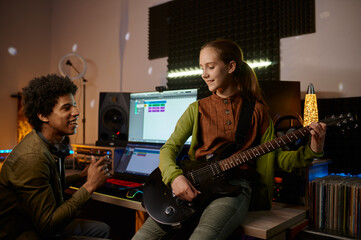 Music producer and teenager girl guitarist at recording studio