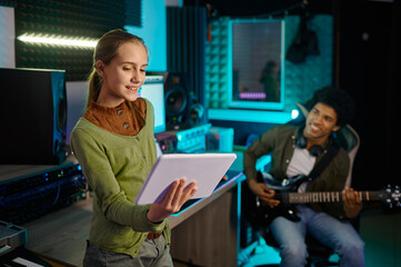 Young girl singing song mixing track with man guitarist