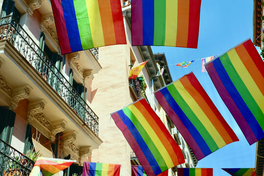 Rainbow festive flags hang between balconies downtown on the streets of Chueca district in Madrid, Spain. Ceremony decorations during gay pride month