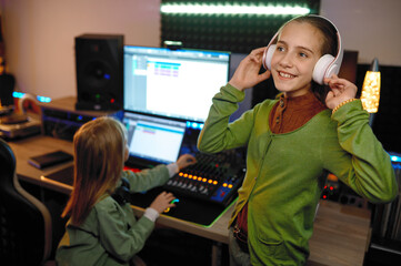 Children at record studio focus on girl listening music in headset