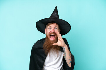 Young wizard in halloween isolated on blue background shouting with mouth wide open