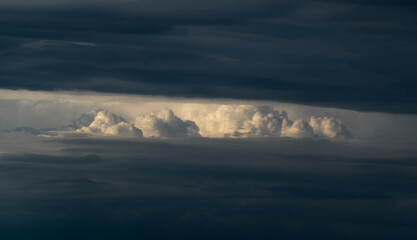 Obraz premium Bright sunlit cloud visible through opening in dark cloud, abstract landscape