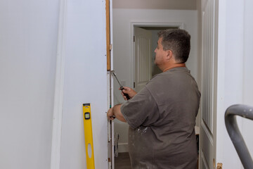 During the installation of interior doors in a new house, a trim worker uses the hammer