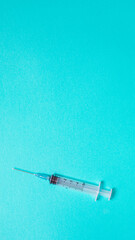 Syringe on pastel blue background from above