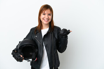 Redhead girl with a motorcycle helmet isolated on white background pointing to the side to present a product