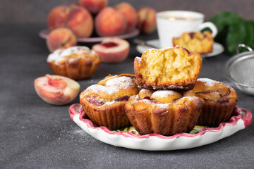 Homemade muffins with peaches on plate on gray background