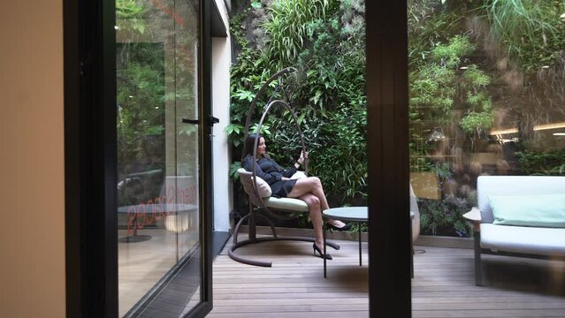 Mujer descansa en un sill&oacute;n mecedora delante de un jard&iacute;n vertical