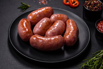 Grilled sausages with spices and herbs on a black background