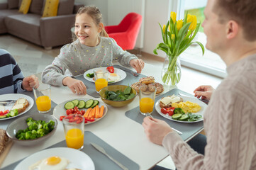 Teen children and their father talking during healthy breakfast at home in the morning before school