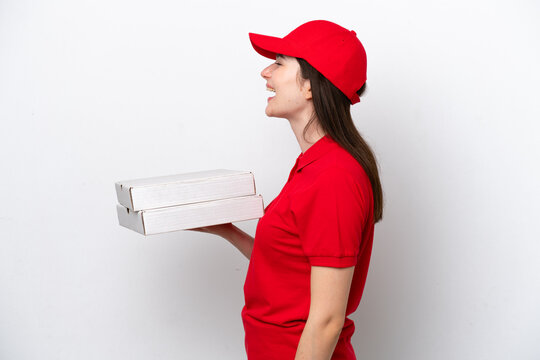 Young Russian pizza delivery picking up pizza boxes isolated on white background laughing in lateral position